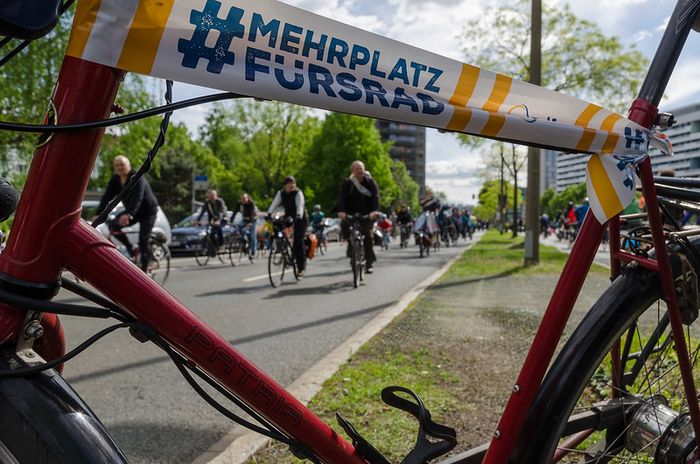 Fahrraddemo auf einer Straße in Dresden, darüber ein Banner mit der Auschrift: #mehrplatzfürsrad